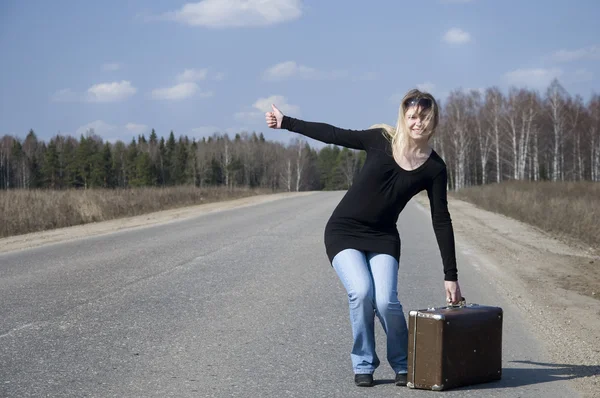 Girl hitchhiking on the road — Stock Photo, Image