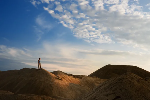 Молодой человек в песчаной пустыне в силуэте заката — стоковое фото