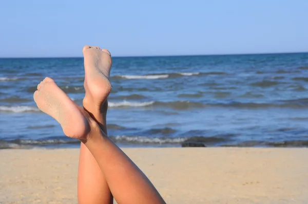 可爱的双腿在蓝蓝的天空上海滩上 — 图库照片