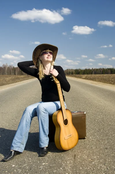 País menina com guitarra senta-se na estrada solitária — Fotografia de Stock