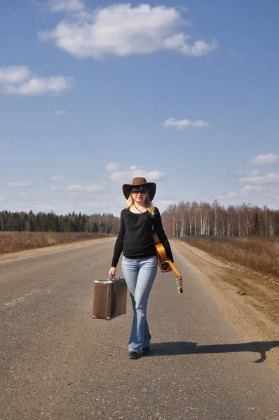Деревенская девушка с гитарой отправляется в одиночную поездку — стоковое фото
