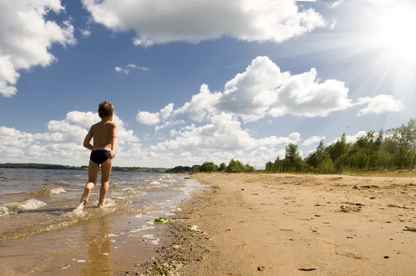 Mladý chlapec běží na krásné pláži — Stock fotografie