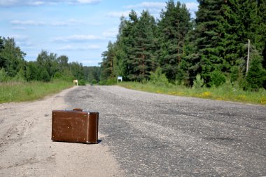 Old suitcase left on a dirt road clipart