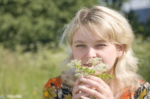 Beautiful girl in fresh grass smelling flower — Stock Photo, Image