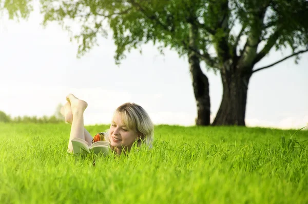 Молода красива жінка лежить на зеленому полі — стокове фото