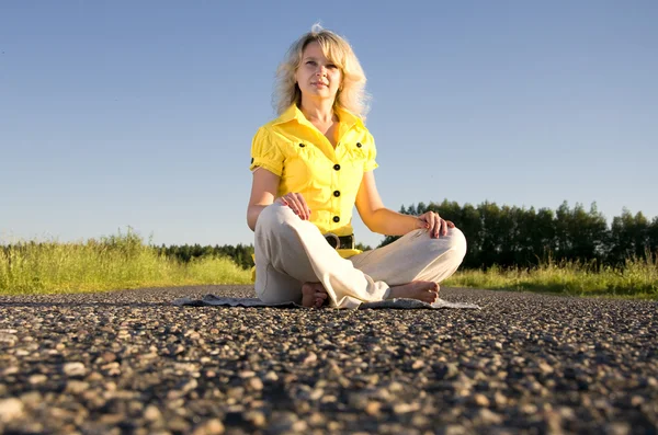 Girl meditates on highway middle in rural — Stock Photo, Image