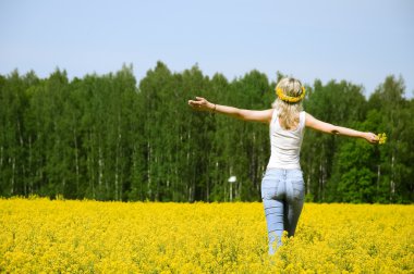 Happy young woman is standing on a field clipart