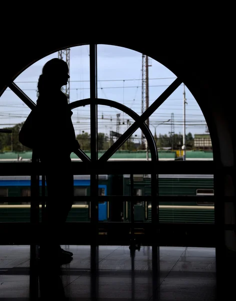 Silhouette woman opposite window railway station