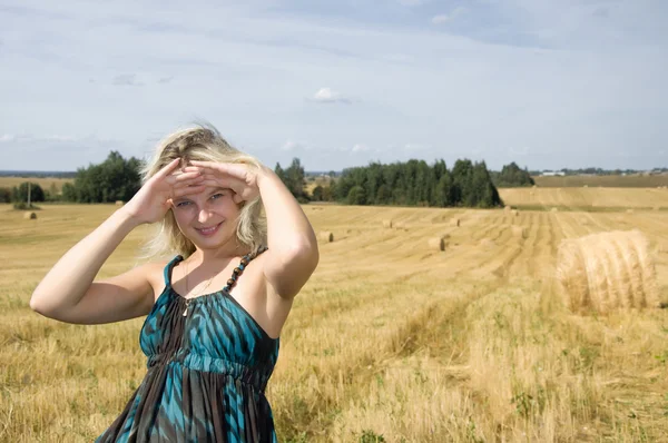 Girl looks out from hay under sky — Stock Photo, Image