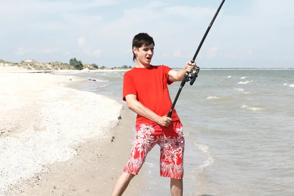 En ung man fångar en fisk — Stockfoto