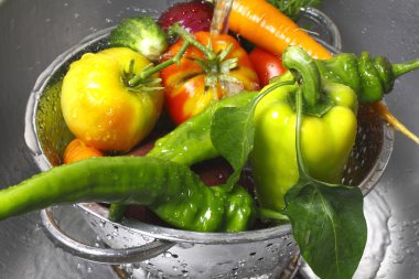 Vegetables in a colander and the water jet clipart