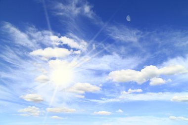 The sun and moon in a blue sky with clouds clipart