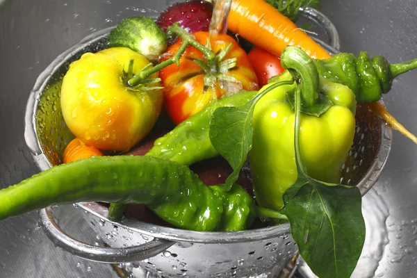 Vegetables in a colander and the water jet — Stock Photo, Image