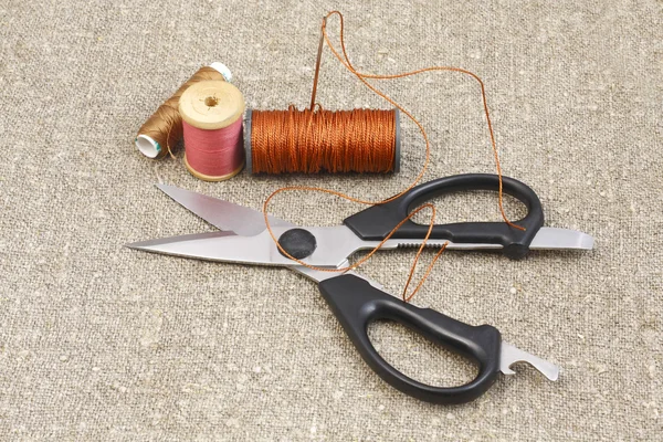 stock image Scissors, needle and thread on canvas of mats