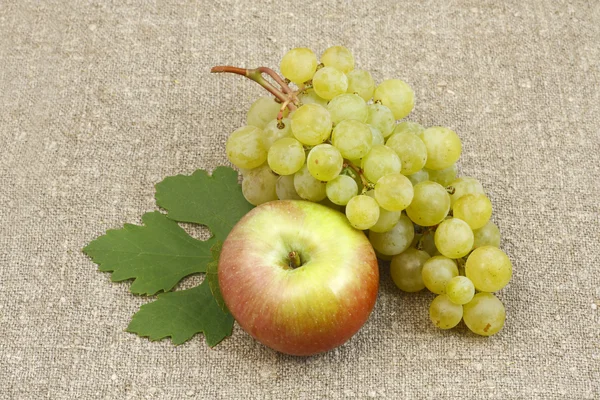 Bunch of white grapes and apples on a background of the matting — Stock Photo, Image