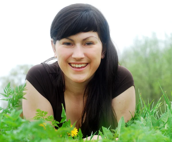 Sonriente hermosa mujer tendida en la hierba — Foto de Stock