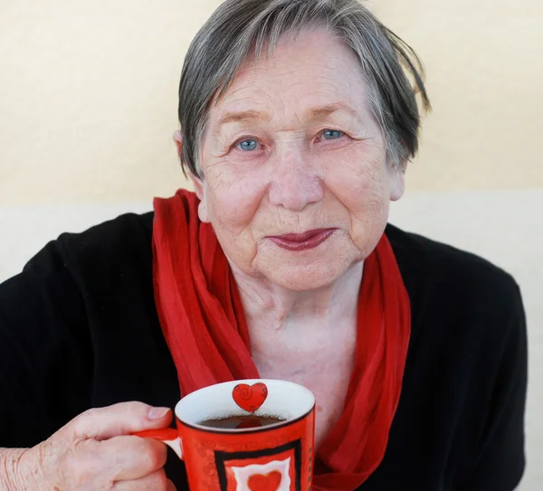 Bir çay bardağı ile gülümseyen büyükanne — Stok fotoğraf