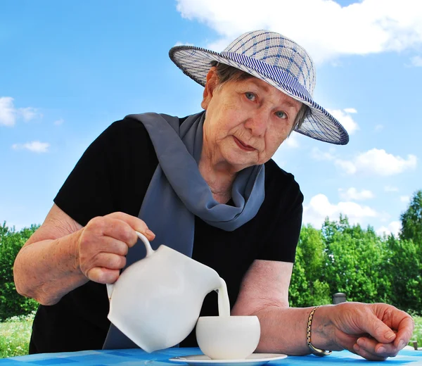 La donna versa il latte da una brocca in una tazza — Foto Stock