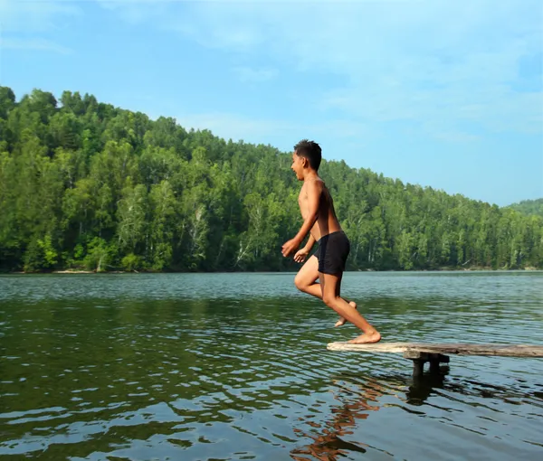 Rapaz saltando no lago — Fotografia de Stock