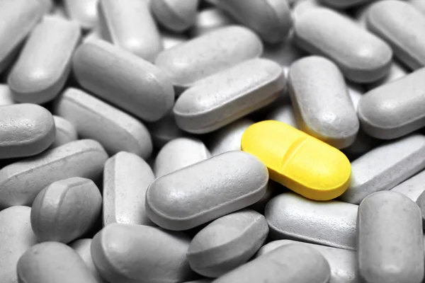 Jeden žlutý prášek na šedé pilulky — Stock fotografie