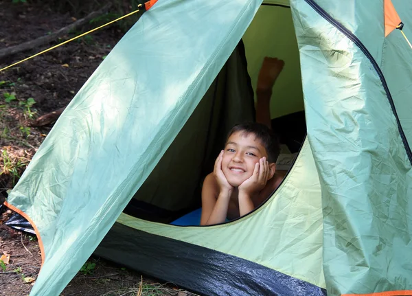Garoto sorridente olhando da tenda — Fotografia de Stock