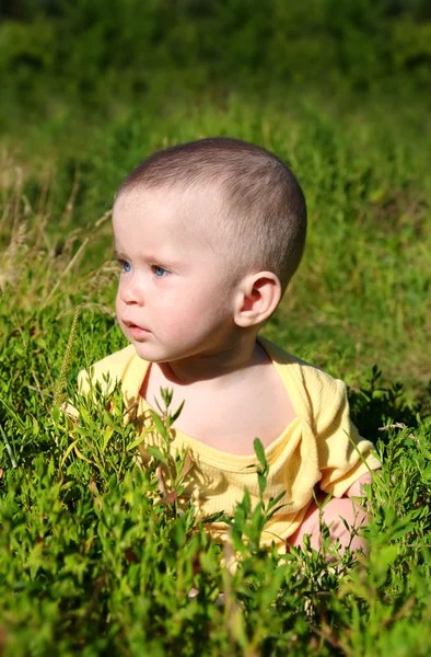 Dziecko siedzi w trawie — Zdjęcie stockowe
