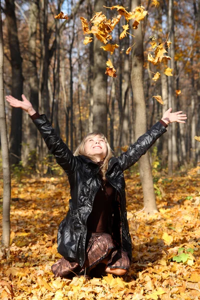 Красива дівчина кидає осіннє листя — стокове фото