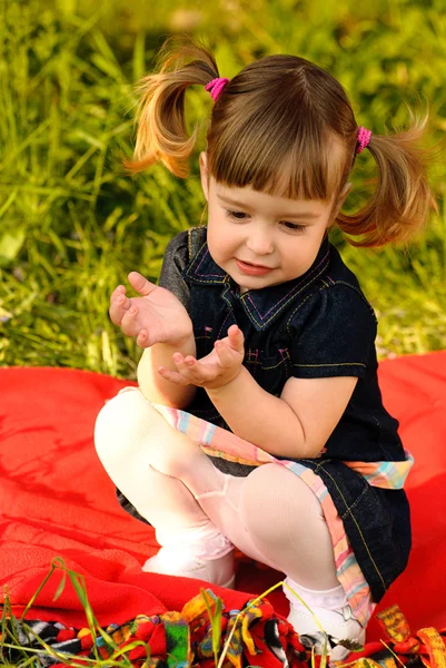 Kleines Mädchen im Garten spricht auf rotem Teppich — Stockfoto