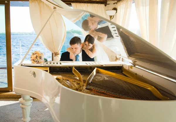 Bride and groom at the grand piano — Stock Photo, Image