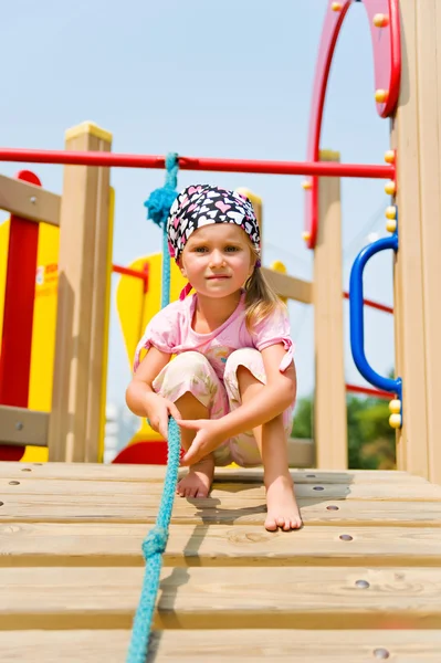 Mooi klein meisje op speeltoestellen — Stockfoto