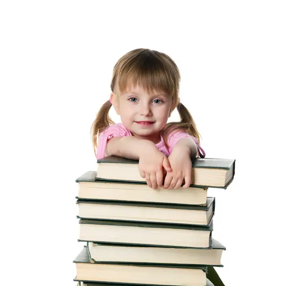 Милая маленькая девочка сидит рядом со стопкой больших книг — стоковое фото