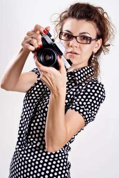 Schöne Frau in einem schwarzen Tupfen-Kleid mit Kamera lizenzfreie Stockfotos