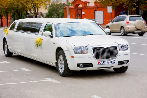 Белый свадебный лимузин на дороге. Украшенный цветами . — стоковое фото