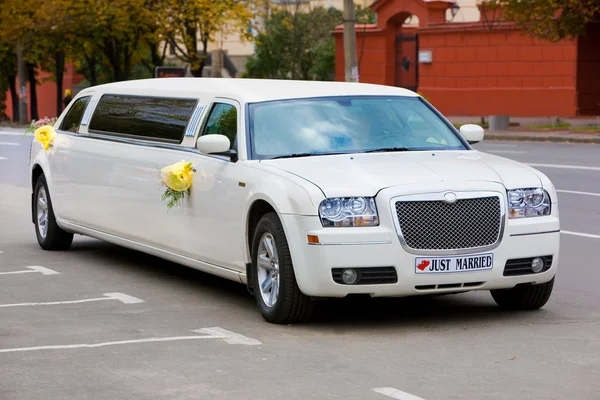 Vit bröllop limousine på vägen. ornated med blommor. — Stockfoto