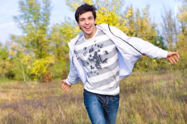 mutlu genç adam, gökyüzü ve ağaçlar arka planı atlama