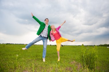 Happy smiling couple jumping in the field clipart