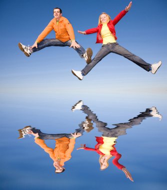 Happy smiling couple jumping in sky. Reflected in water clipart