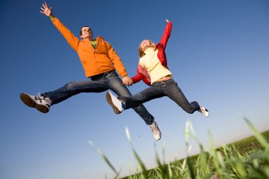 Happy smiling couple jumping in blue sky clipart