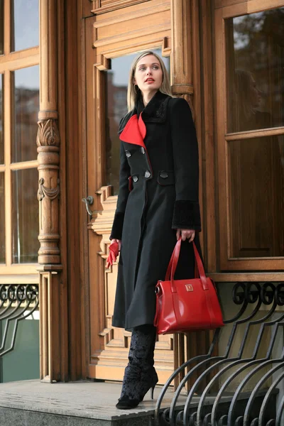 黒いコートの美しい若い女性のステップの上に立つ — ストック写真