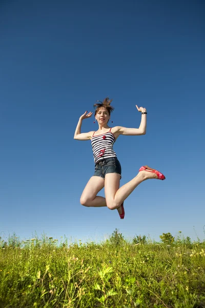 Glückliche junge Frau springt in ein Feld — Stockfoto