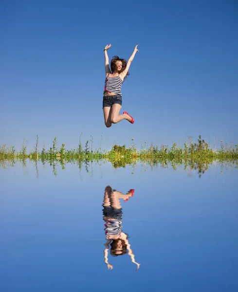 Lycklig ung kvinna hoppar i ett fält — Stockfoto