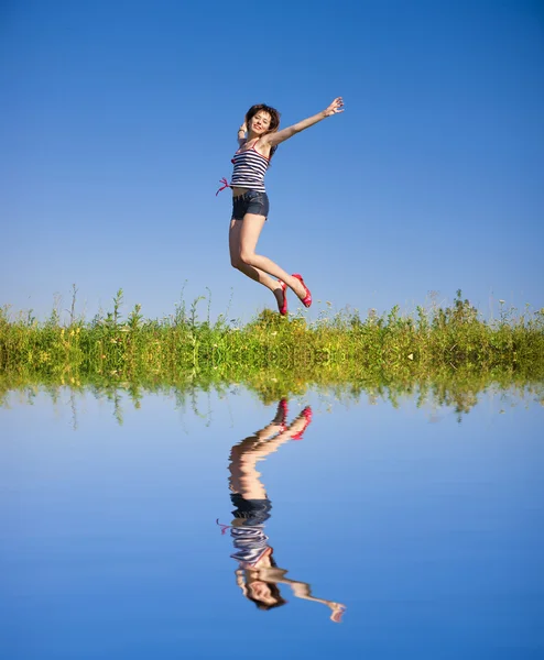 Gelukkige jonge vrouw springen in een veld — Stockfoto