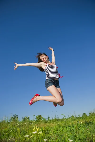 Счастливая молодая женщина прыгает в поле — стоковое фото