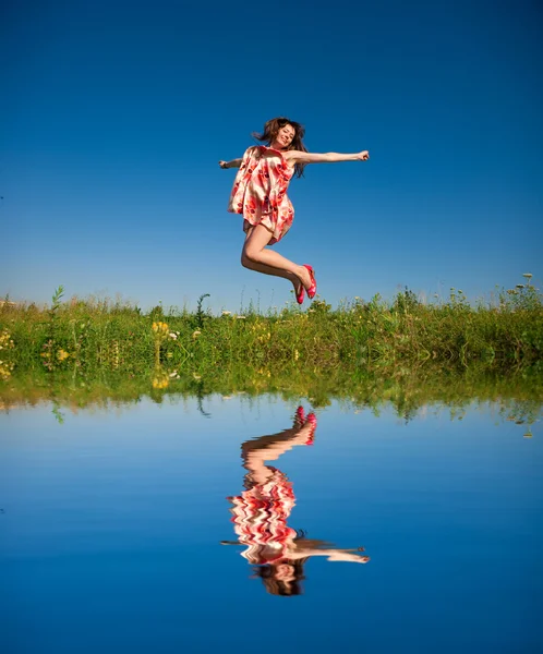 Glückliche junge Frau springt in ein Feld — Stockfoto