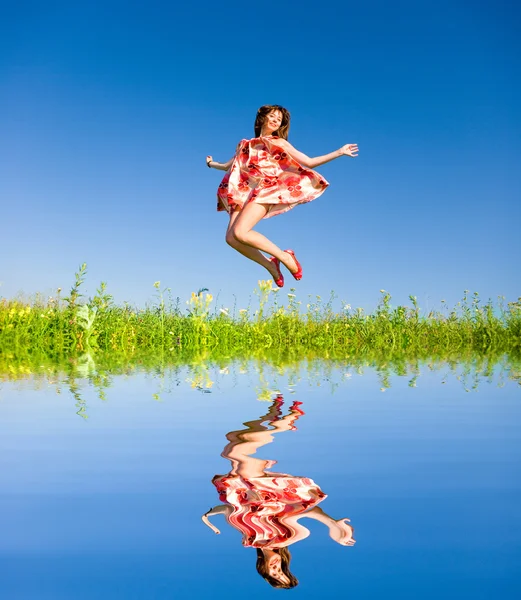 Feliz joven mujer está saltando en un campo —  Fotos de Stock