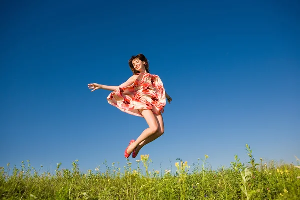 Happy young woman jumping in a field — Stock Photo, Image