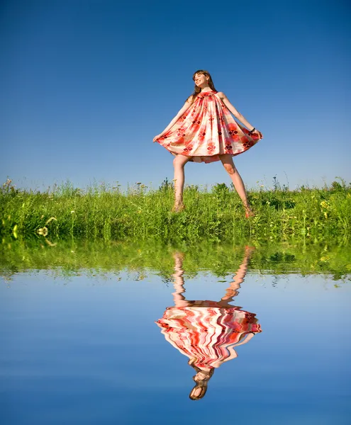 Gelukkig meisje vlucht op een weide. in de rode jurk en rode schoenen. agai — Stockfoto