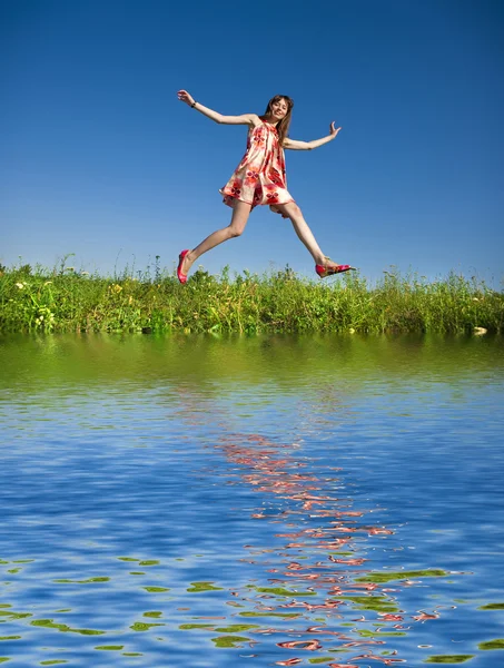 Gelukkige jonge vrouw springen in een veld — Stockfoto