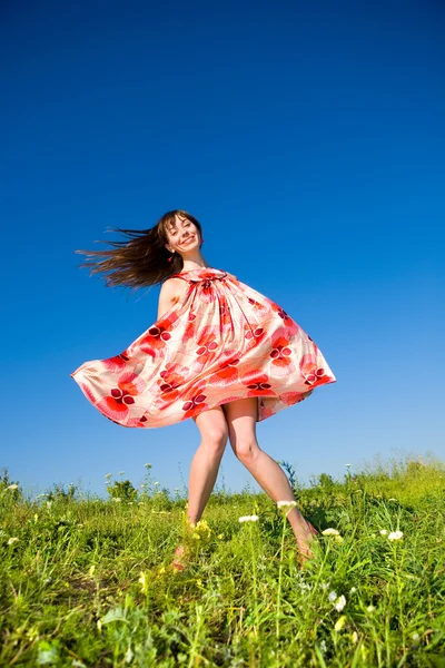 Glückliches Mädchen auf der Flucht auf einer Wiese. in rotem Kleid und roten Schuhen. agai — Stockfoto