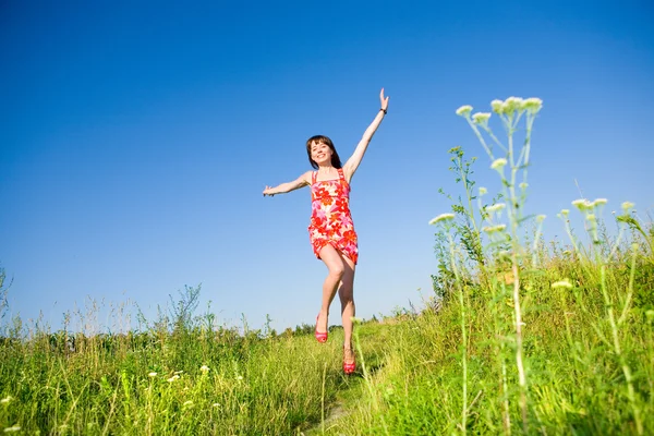 행복 한 여자는 풀밭에 달아 나입니다. 빨간 드레스에 빨간 구두. 기사 — 스톡 사진